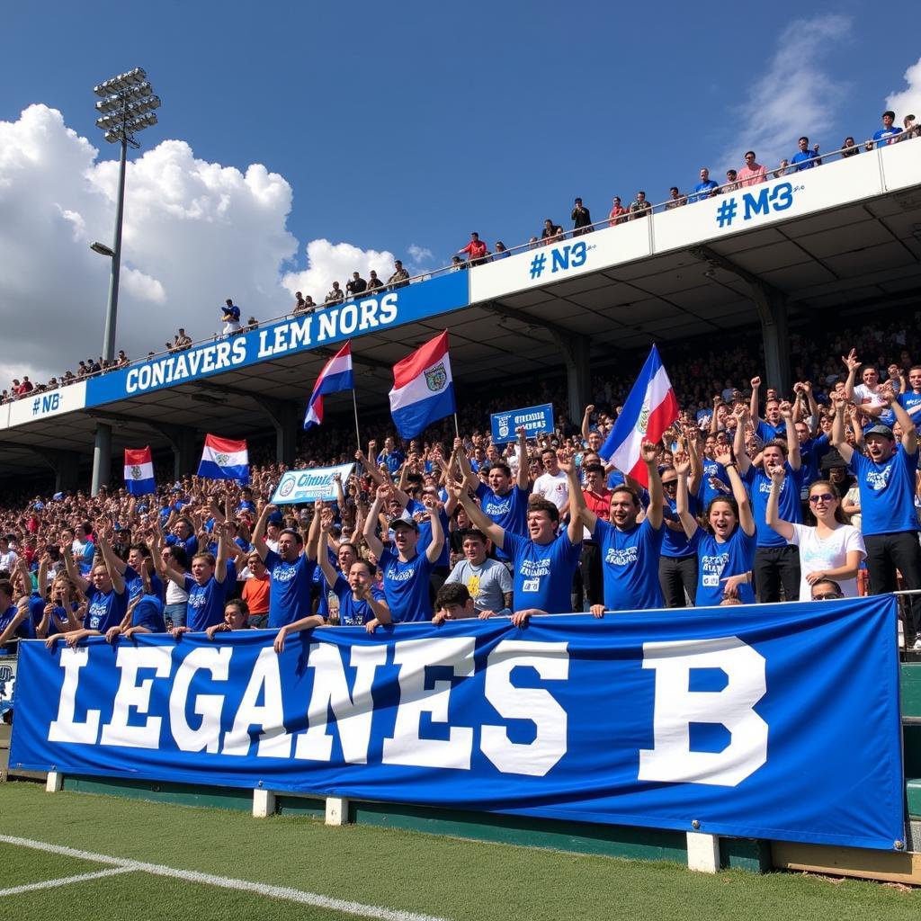 Các cổ động viên Leganes B đang reo hò cổ vũ cho đội bóng. Họ mang theo cờ, băng rôn và hát vang những bài ca cổ vũ. Niềm đam mê và sự ủng hộ của người hâm mộ là nguồn động lực to lớn cho các cầu thủ trẻ.